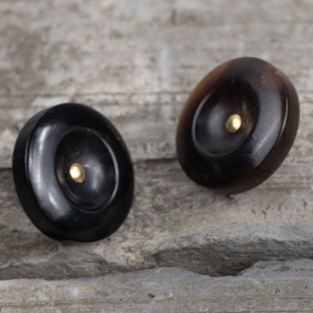 Black horn shank buttons with brass studs on wide, deep-edged fronts