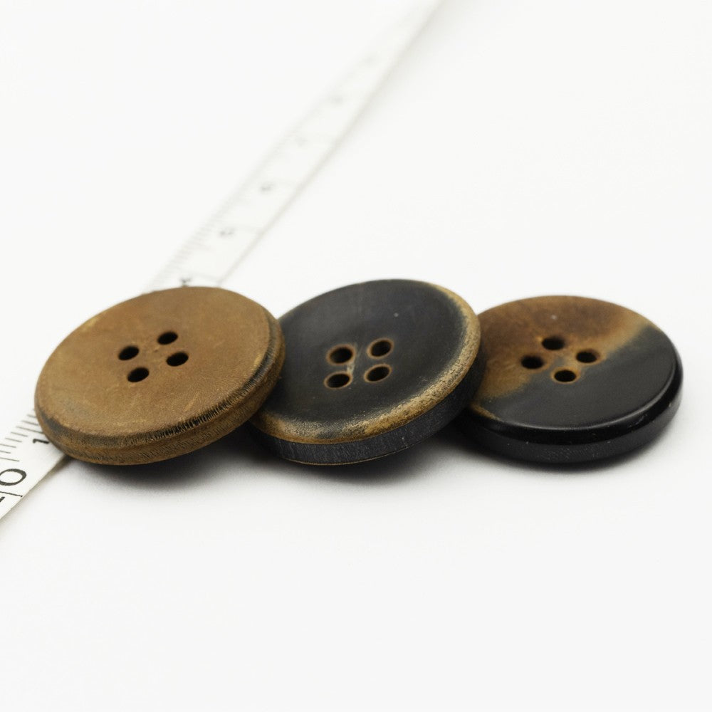Three flat retro horn buttons, tan and black tones, four-hole fronts, assorted finish