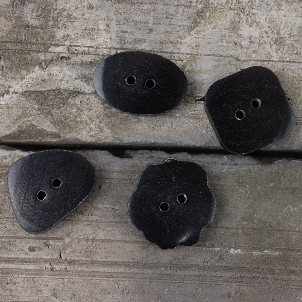 Assorted black horn buttons with two holes: oval, triangle, and flower shapes