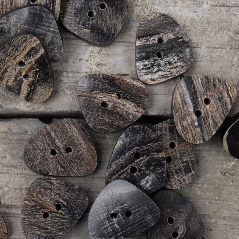 Assorted black horn buttons with two holes in triangle, oval, and square forms