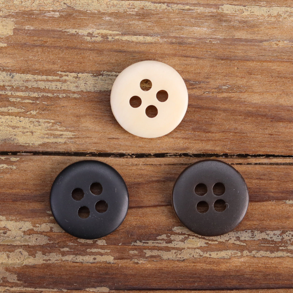 Resin shirt buttons in cream and dark gray, fire-burned rim, four-hole bowl shape