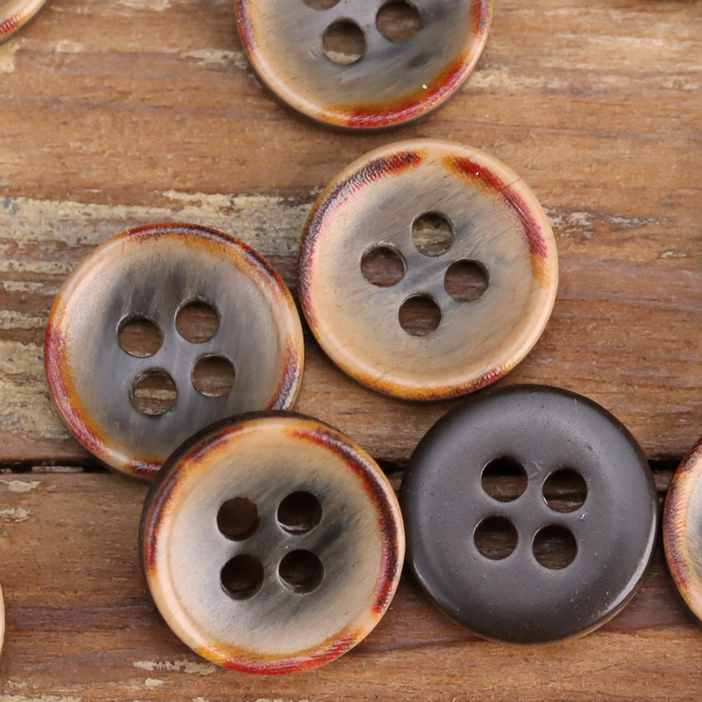 Fire-burned resin shirt buttons close-up, mixed cream and dark with four holes