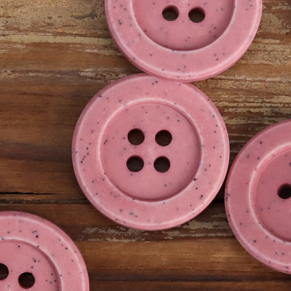 Pink distressed stone coat buttons, close-up: round design with 4 holes and speckled finish