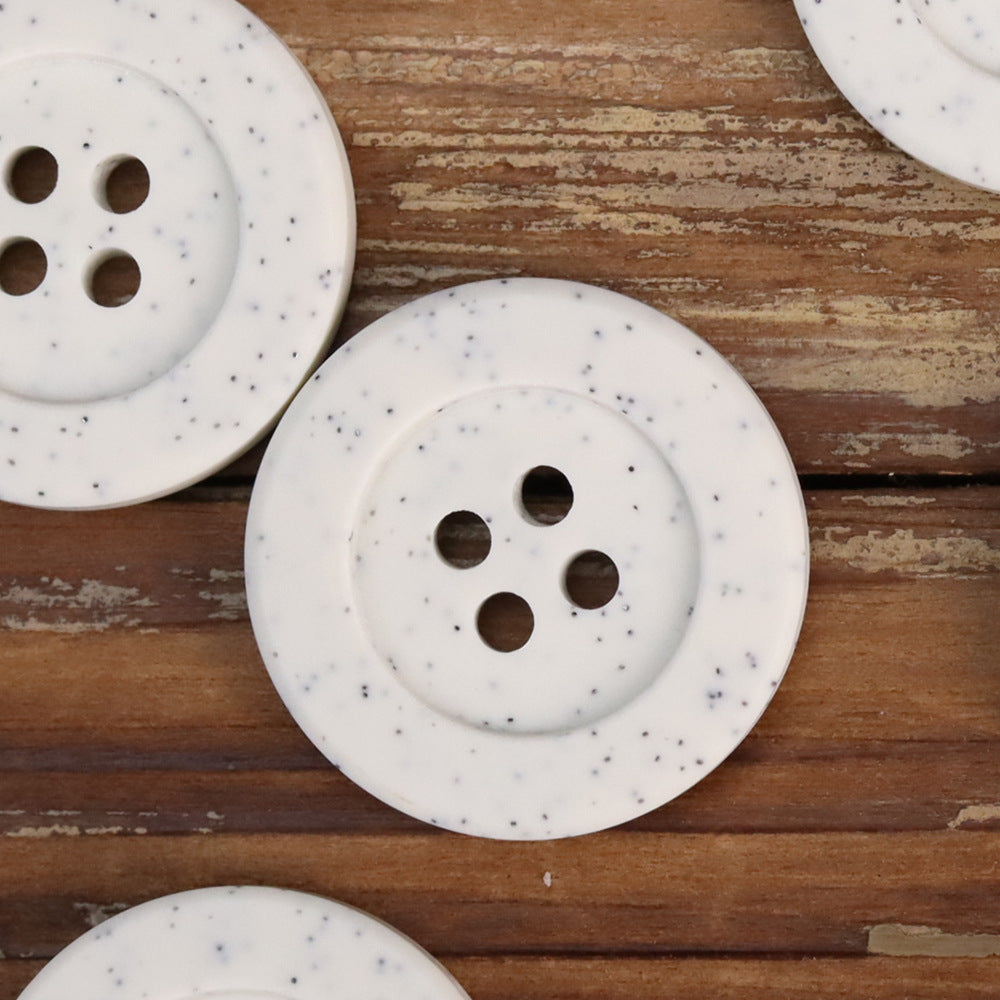 White distressed stone coat buttons close-up: round 4-hole design with speckled finish