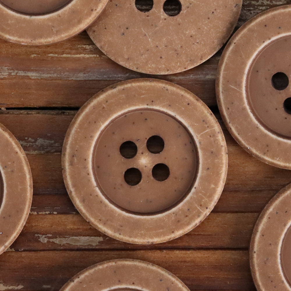 Coffee distressed stone coat buttons close-up: round 4-hole design with speckled finish