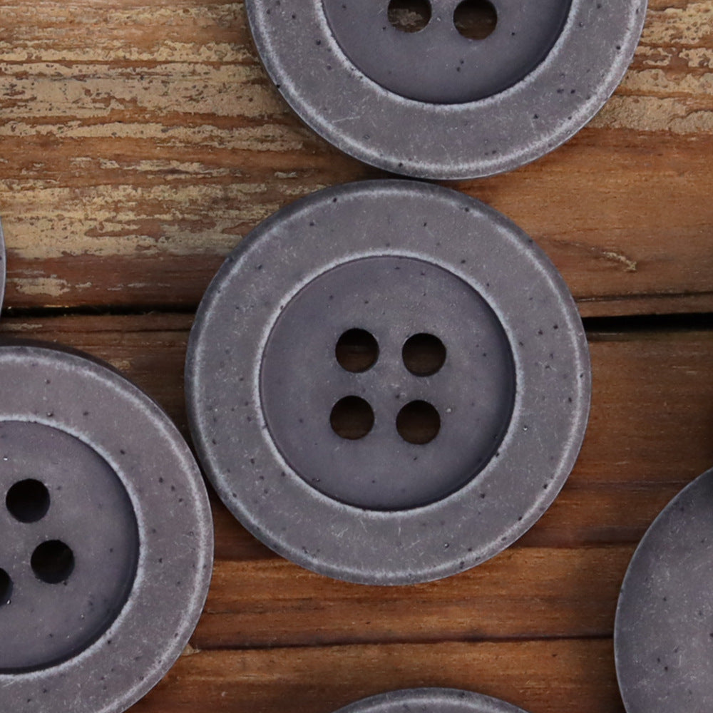 Dark gray distressed stone coat buttons close-up: round 4-hole design with speckled finish