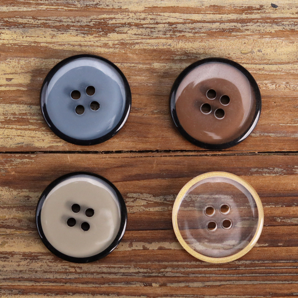Four-hole transparent resin jacket buttons in blue, brown, and off-white; round flat design