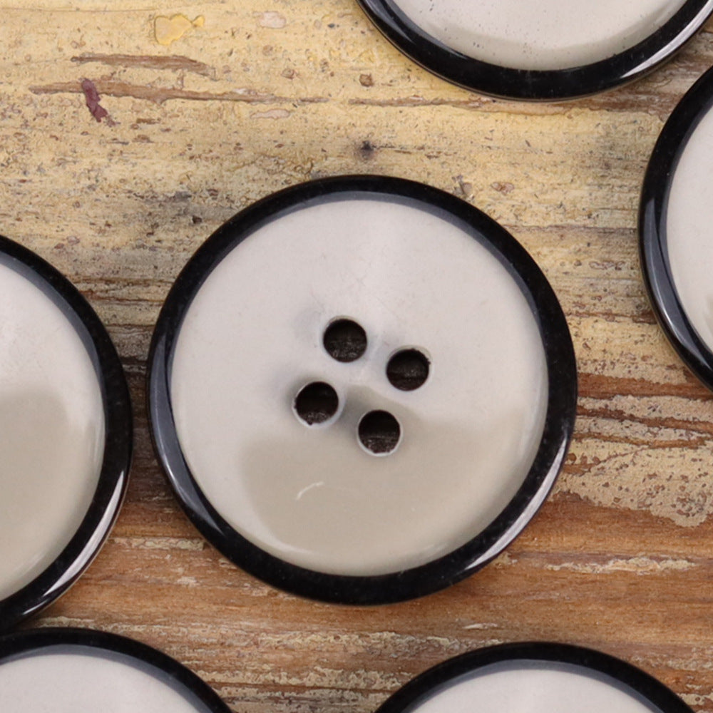 Four-hole transparent resin button in white with black rim, round jacket button view