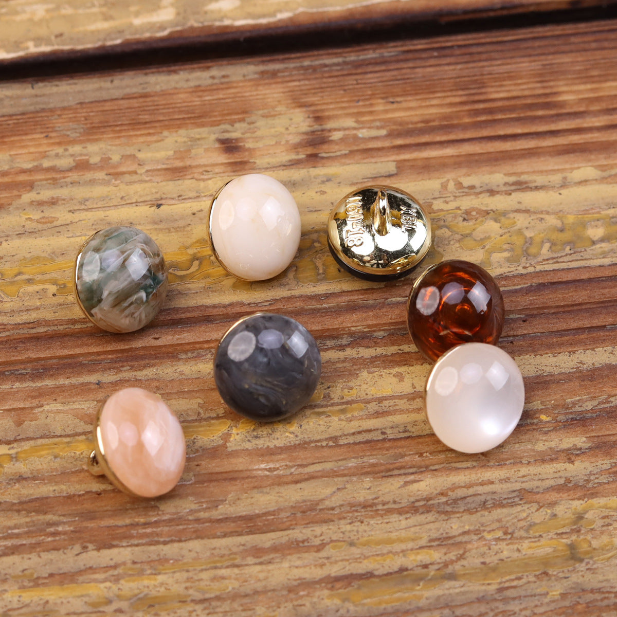 Round cat’s eye resin buttons with metal shank, shown with pale, gray, black, amber, gold