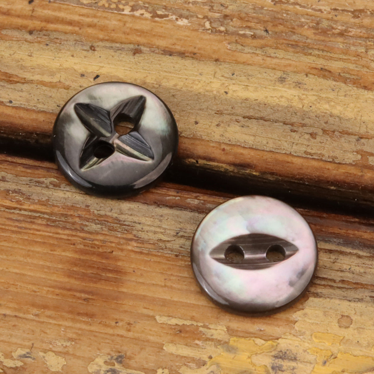 Iridescent shell shirt buttons with starburst pattern, front views on wood