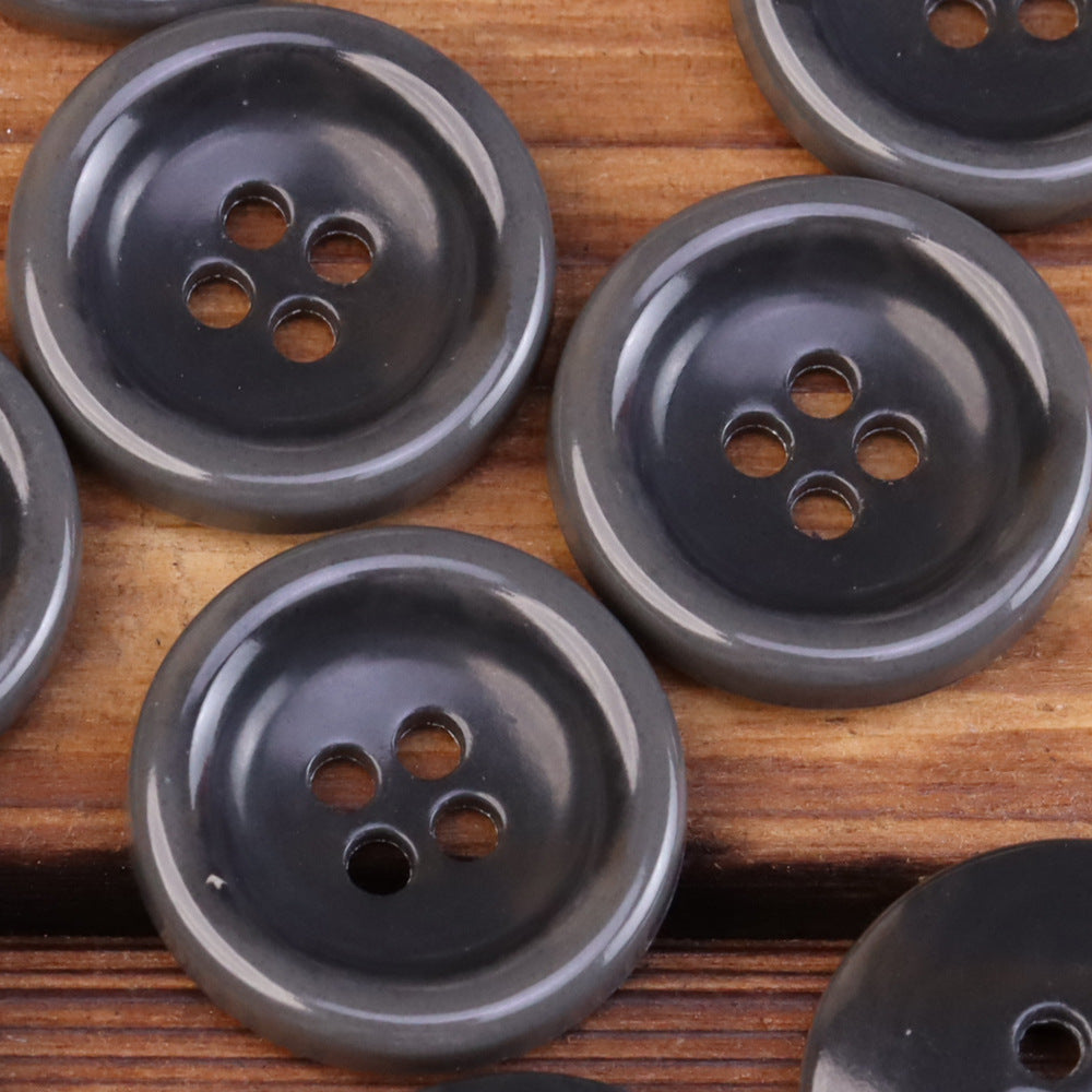 Dark gray round 4-hole urea jacket buttons with imitation horn texture, close-up