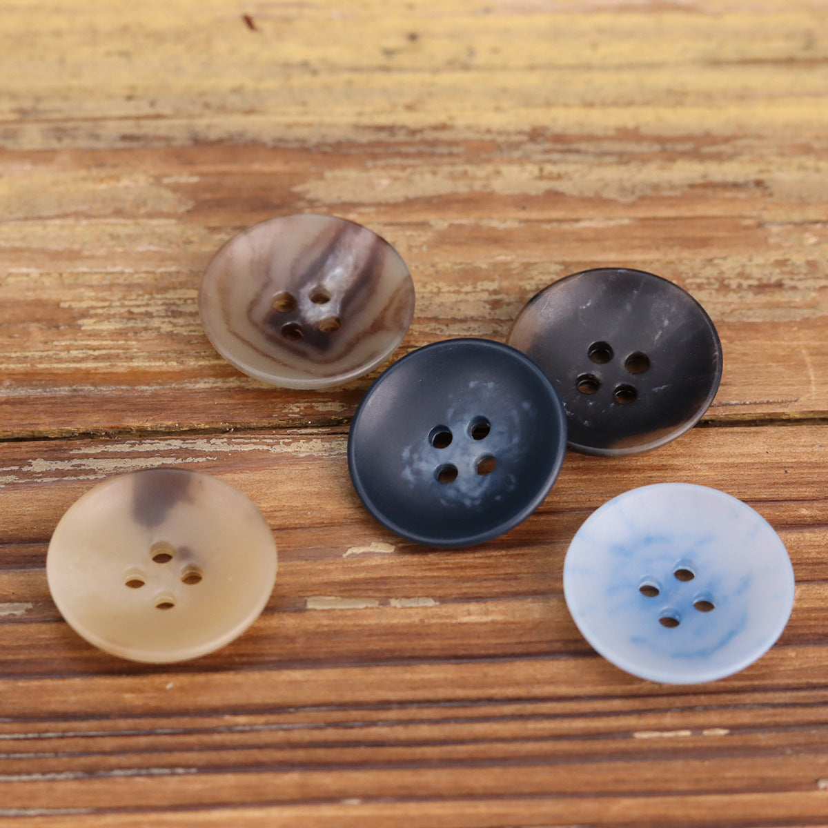 Round 4-hole buttons in light blue, dark navy, beige, and brown tones, bowl-shaped