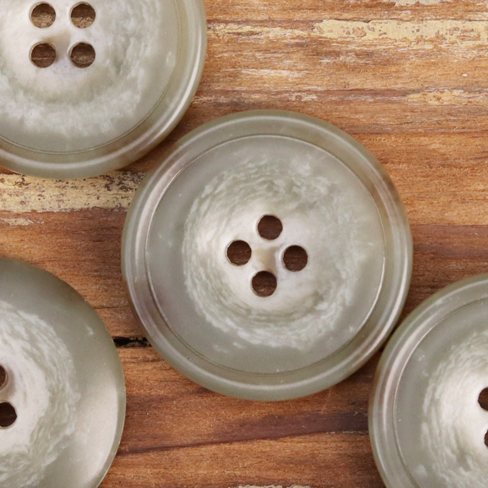 Light green 15–25mm four-hole urea buttons, round with four sew holes, close-up