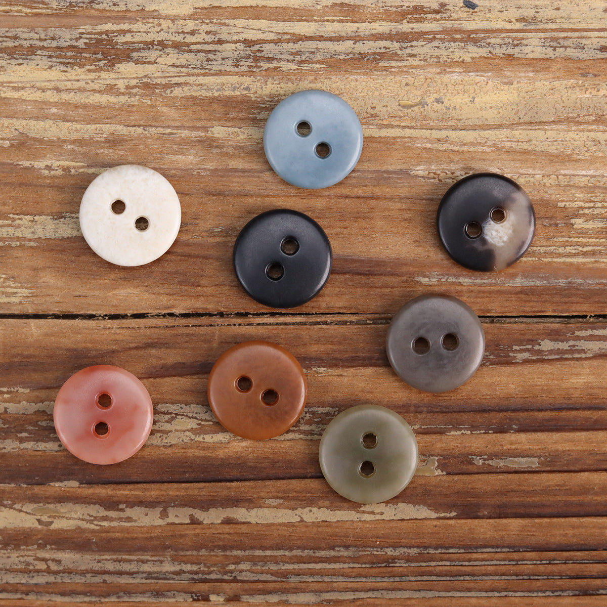 Set of round two-hole cardigan buttons in dark, blue, tan, white, rust, and rose tones
