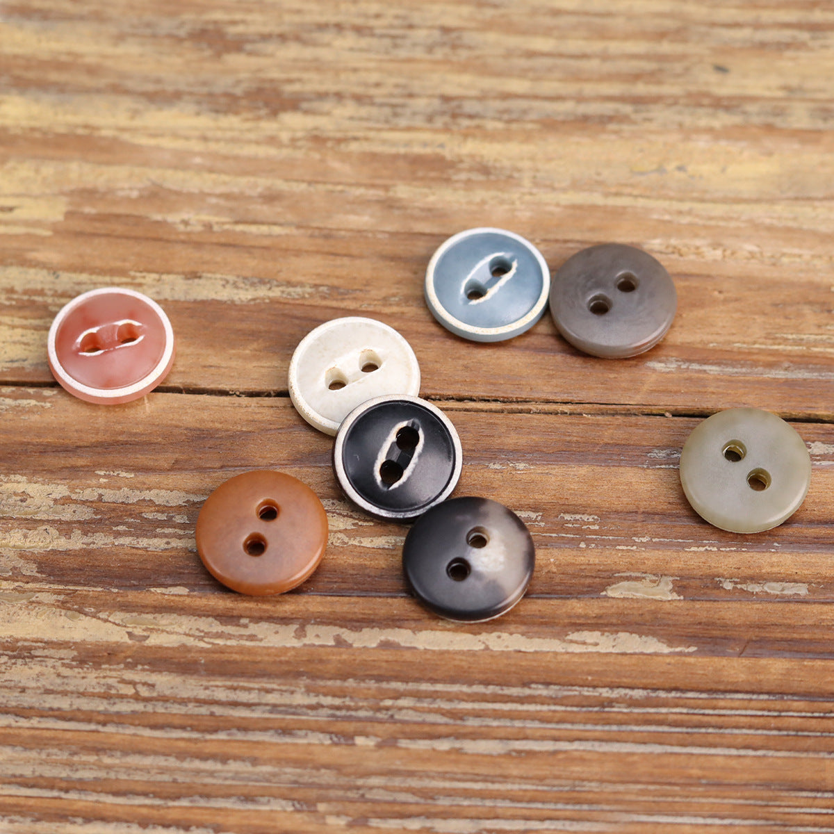 Round two-hole cardigan buttons in burned urea, including light cream, rust, blue, and black