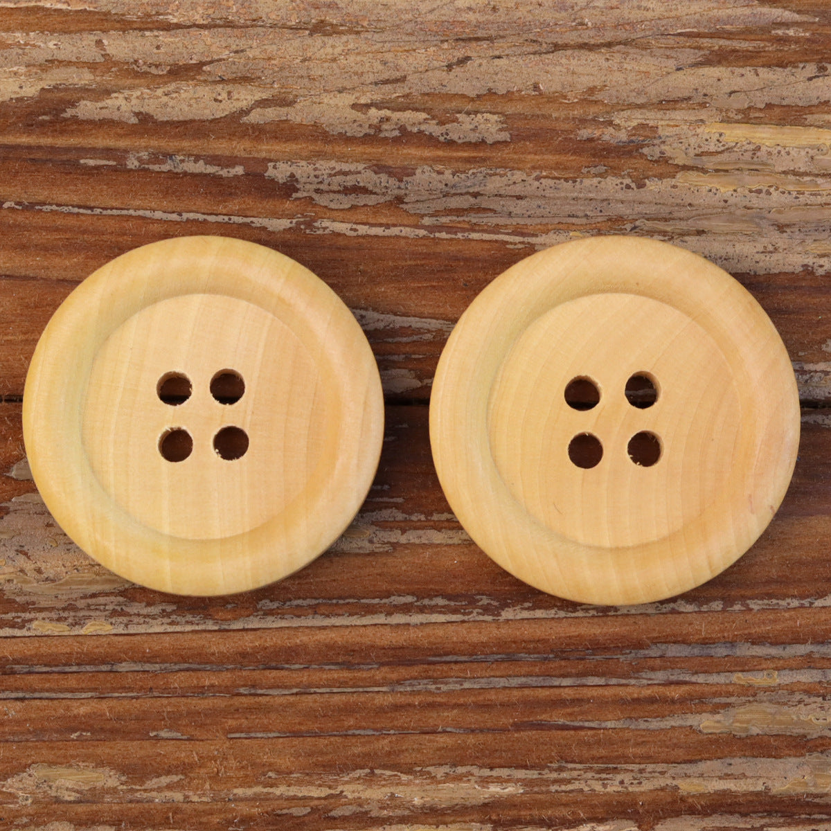 Two larger natural round 4-hole wood buttons, light tan woodgrain look