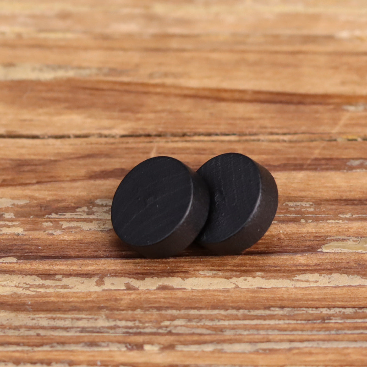 Black flat wooden button pair, top view with smooth matte finish