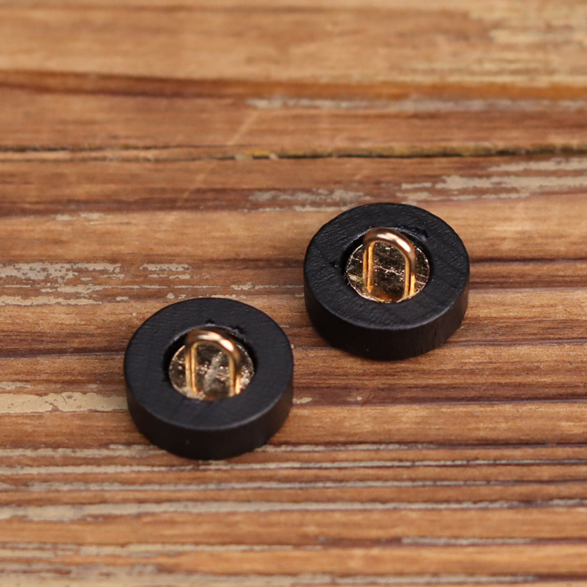 Black wooden buttons showing gold-toned metal loop backs