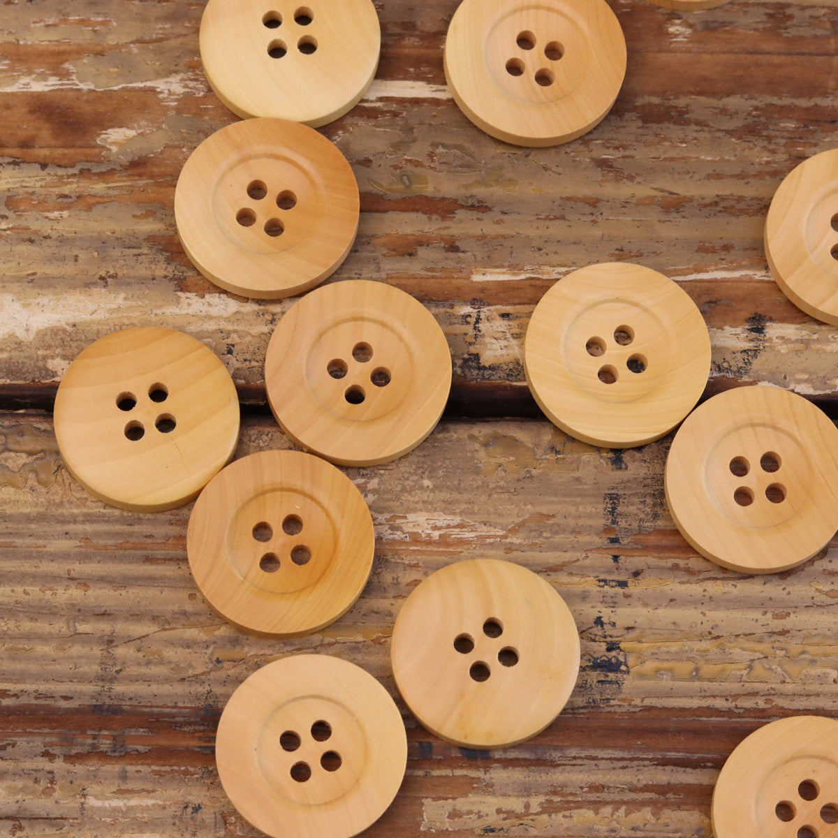 Set of light yellow wood wide-rim four-hole wooden buttons, round face, front views