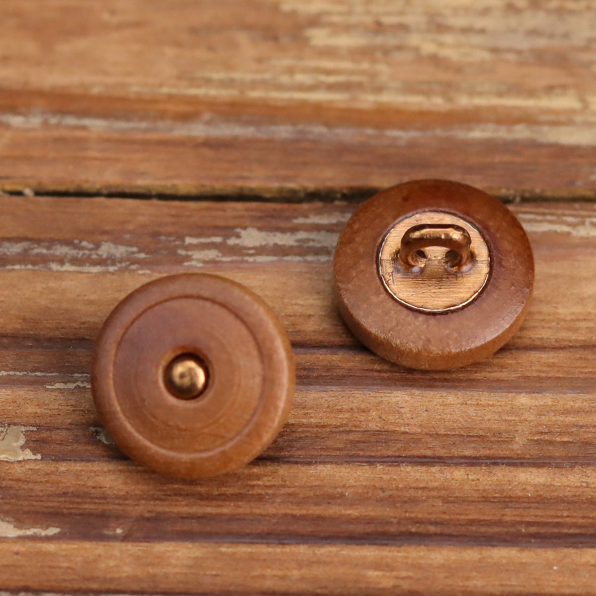 Brown round wooden button front with metal eyelet, visible wood grain and stitching rim