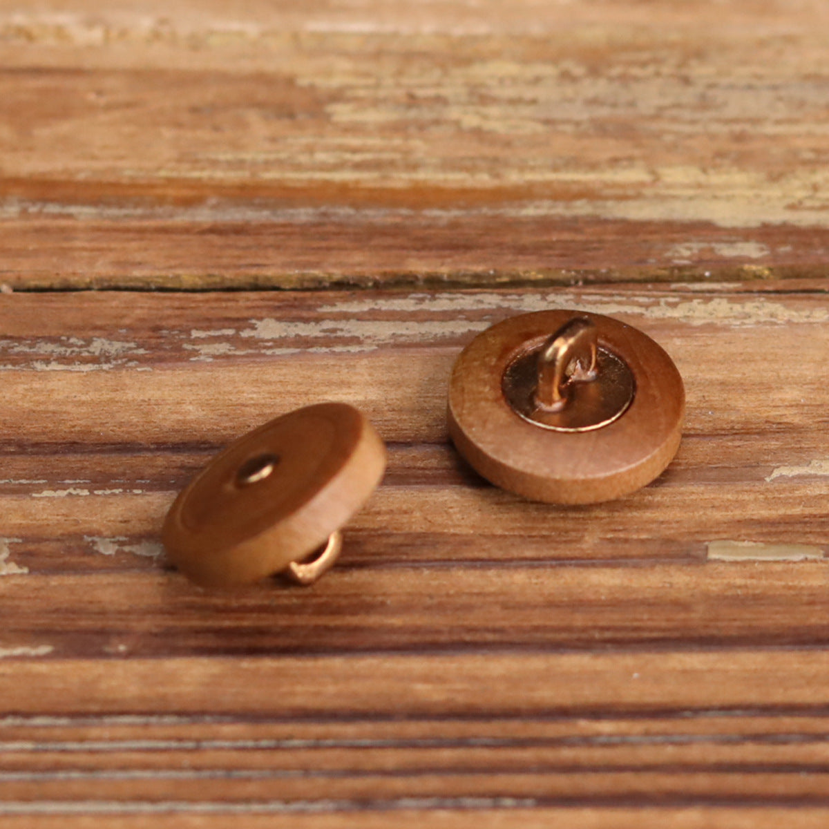 Brown round wooden button underside with metal loop/feet for hand sewing