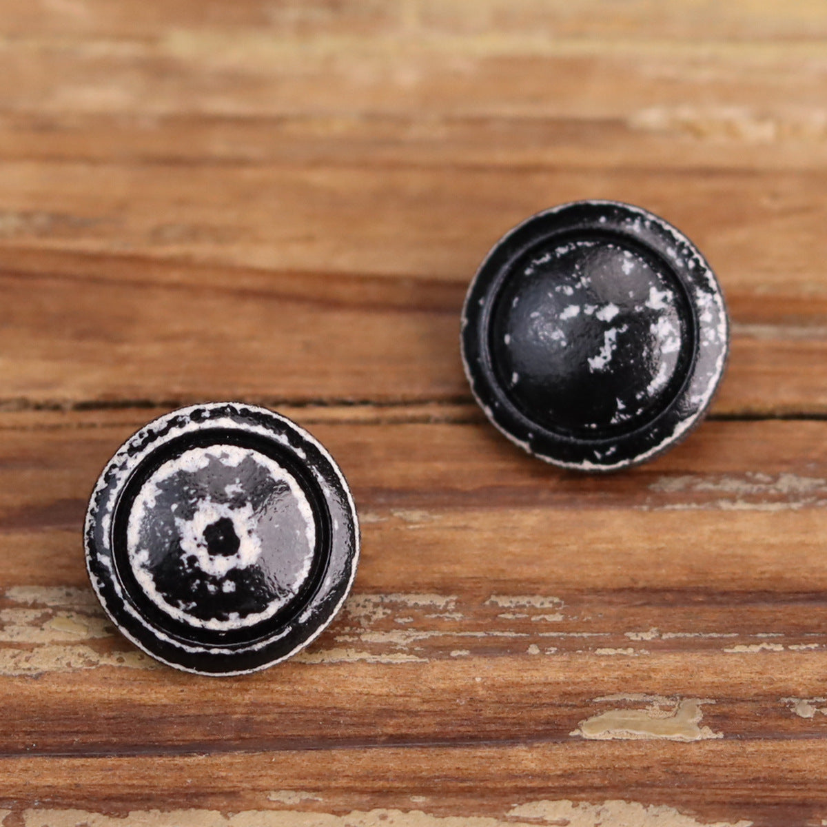 Round black lacquered wooden buttons with white distressed ring trim on the face