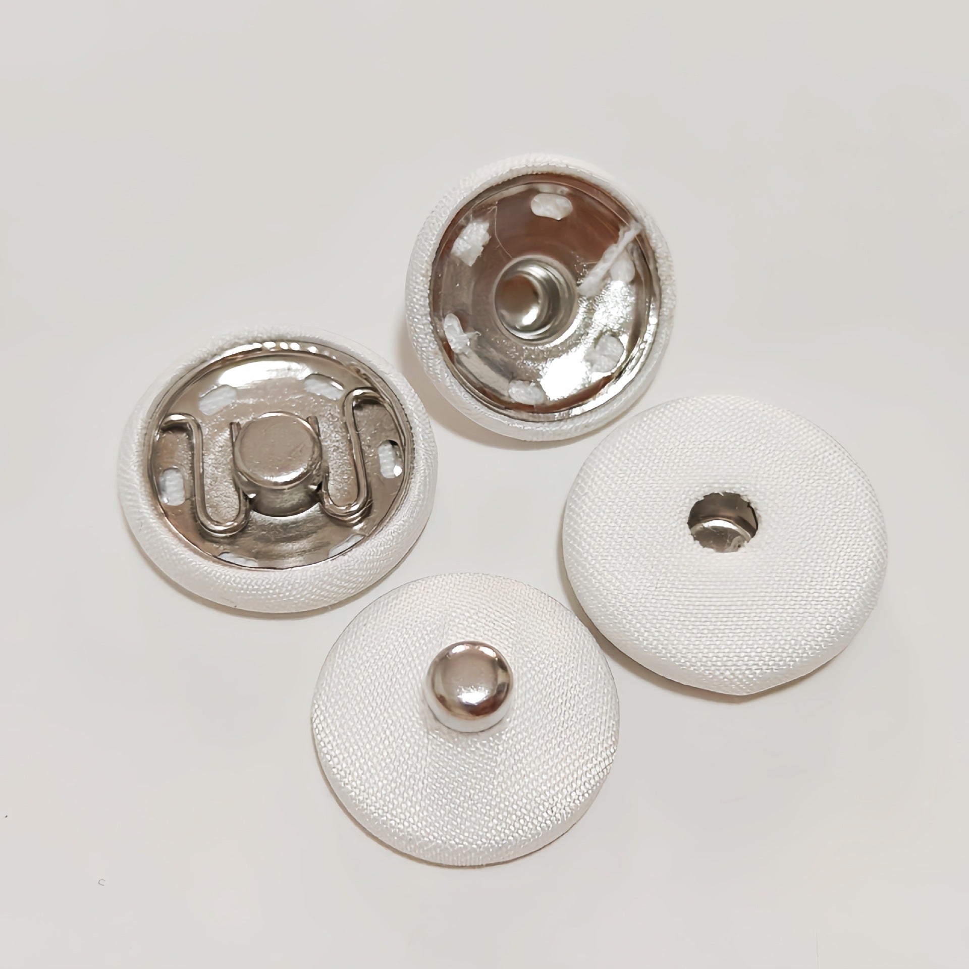 White fabric-covered invisible snap buttons with metal backs visible