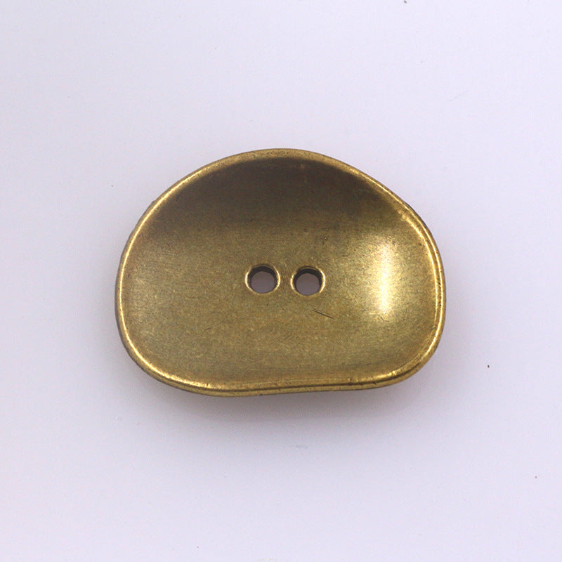 Irregular two-hole metal button, antique gold finish, rounded oval shape
