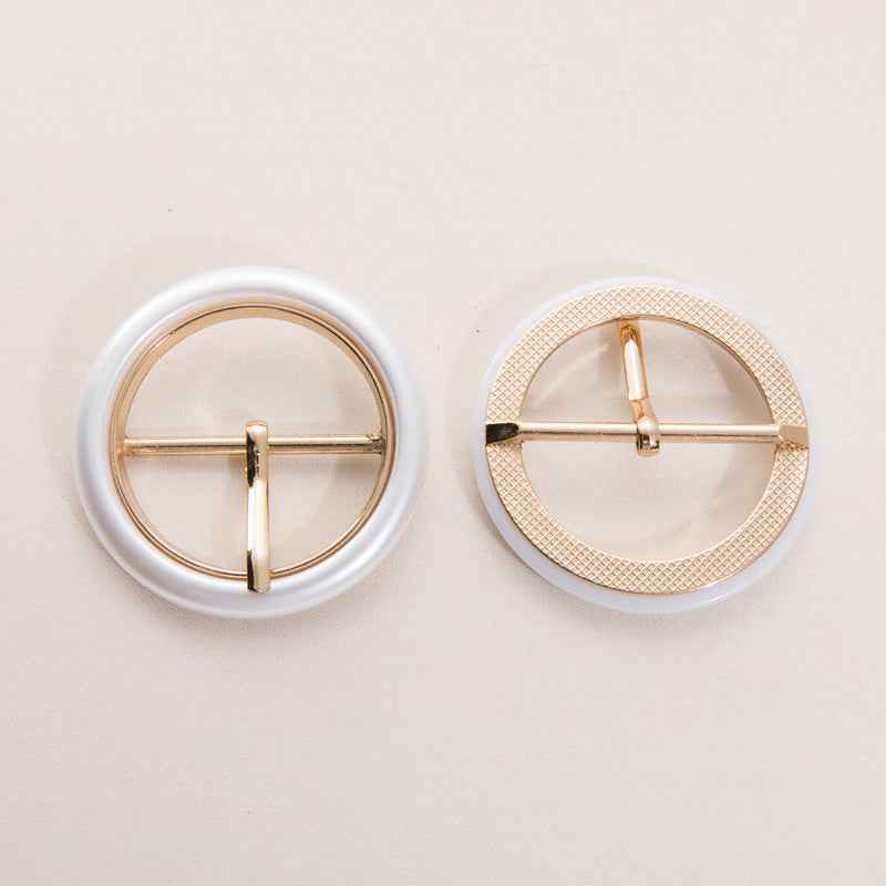 Round belt buckle in pearl white resin with textured edge and gold center bar