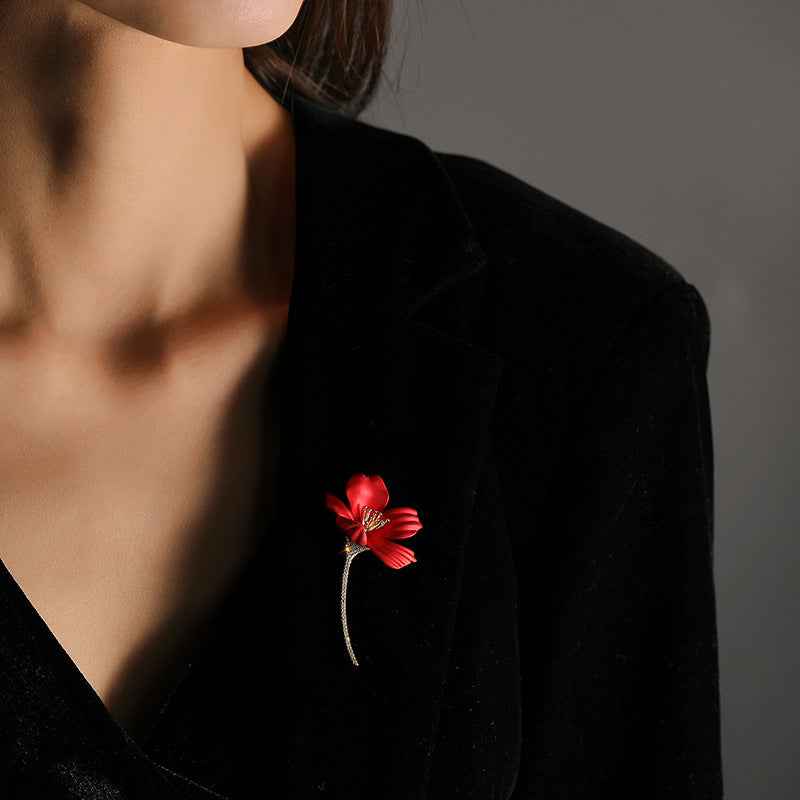 Rote Hibiskus-Anstecknadel am Revers mit glitzerndem goldfarbenem Stiel