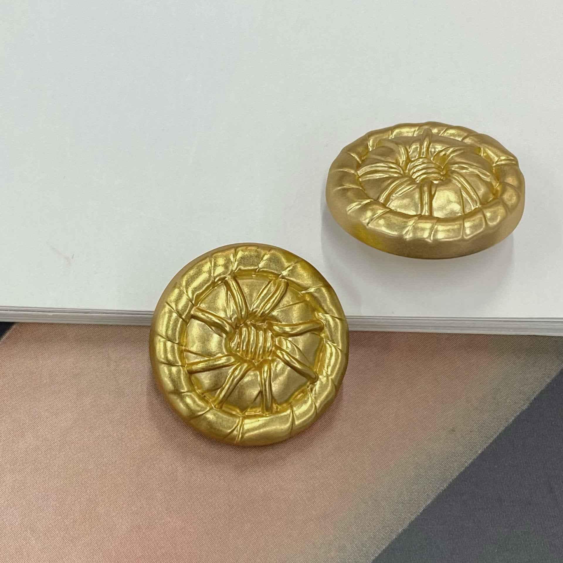 Gold round 3D metal shank button with embossed floral burst detail