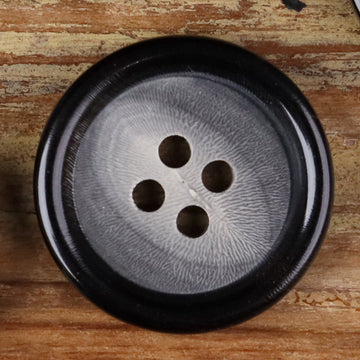 Close-up of a 4-hole round horn-style button with four holes on a dark face