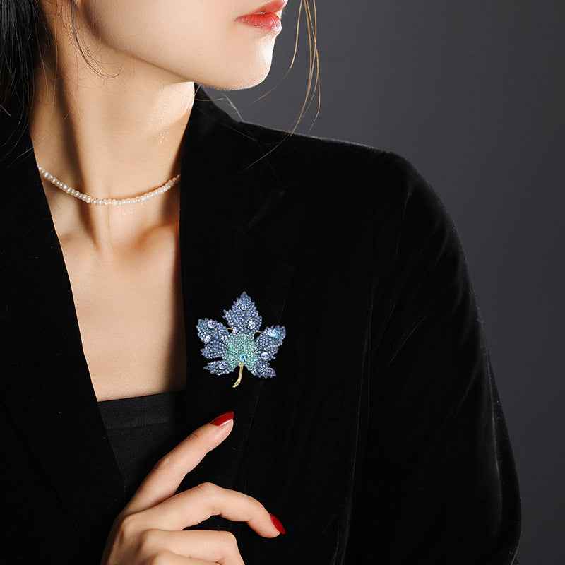 Blue maple leaf brooch pin worn on a dark coat lapel