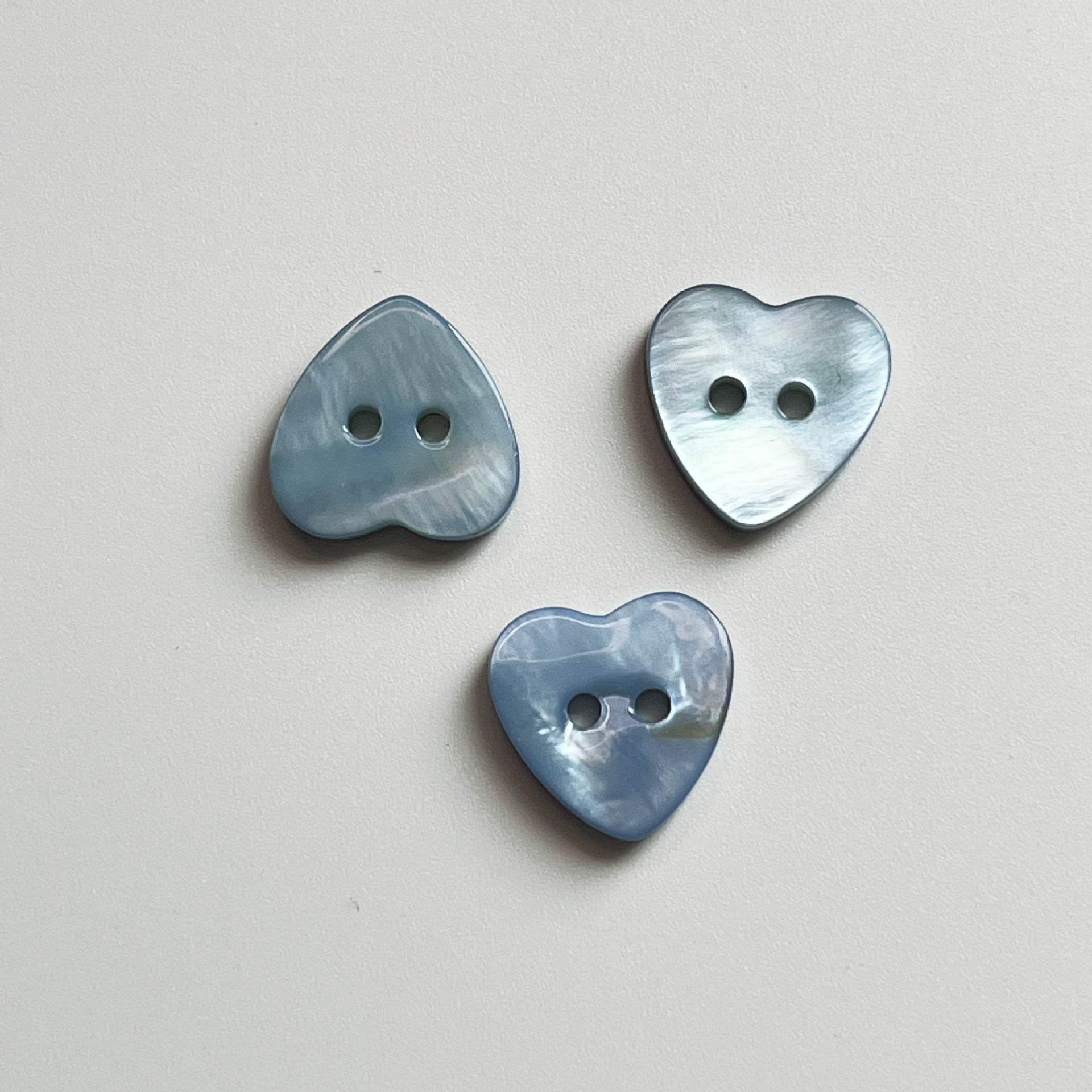 Sky blue heart-shaped 2-hole shirt buttons for children, three buttons shown.