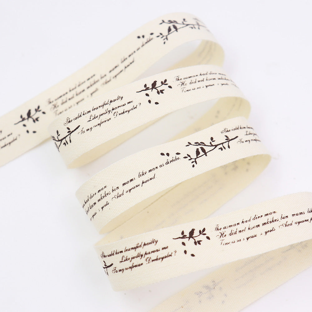 Cremefarbenes Schrägband mit dunklen floralen Zweig-Prints und Spruchtext, mehrere Lagen