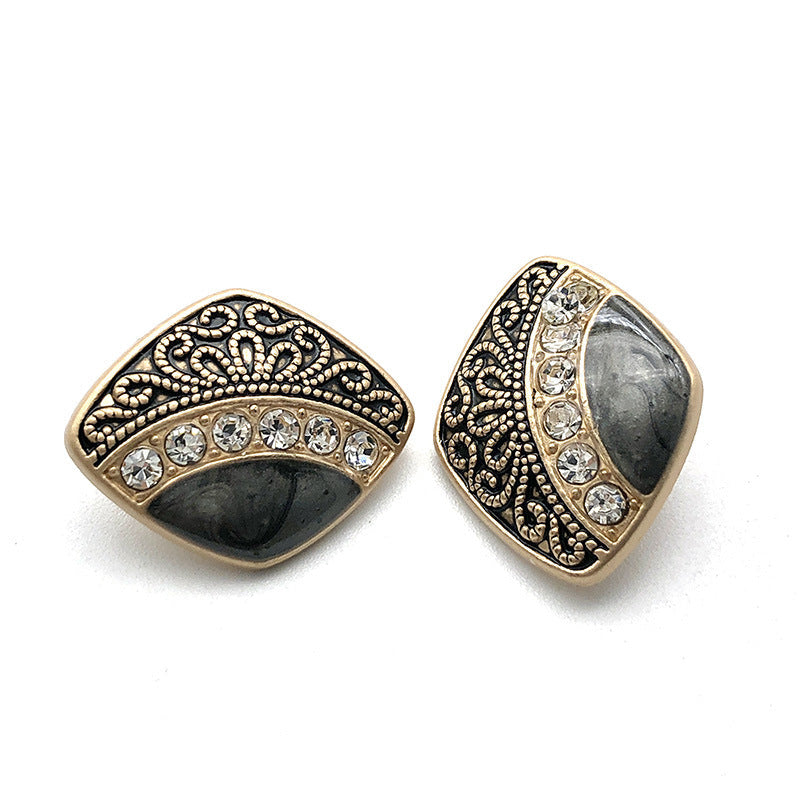 Metal shank button with black enamel, ornate filigree, and clear rhinestone row