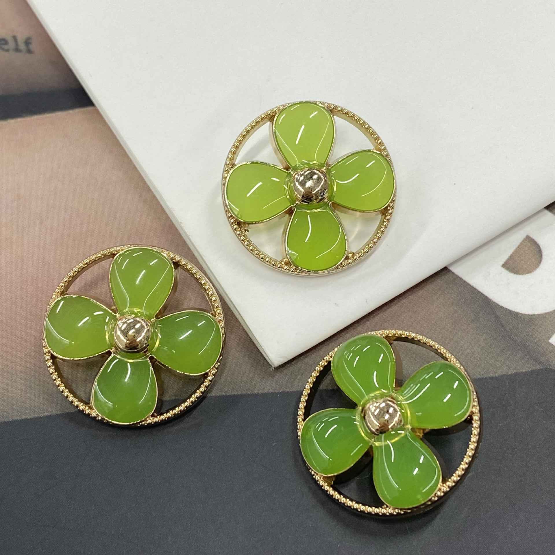 Round clover shank buttons with green petals, gold-tone rim and 5-petal flower center