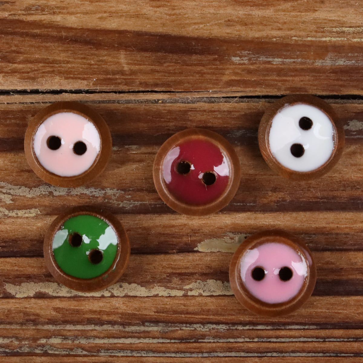 Round 2-hole wood shirt buttons in assorted colors on a wooden surface