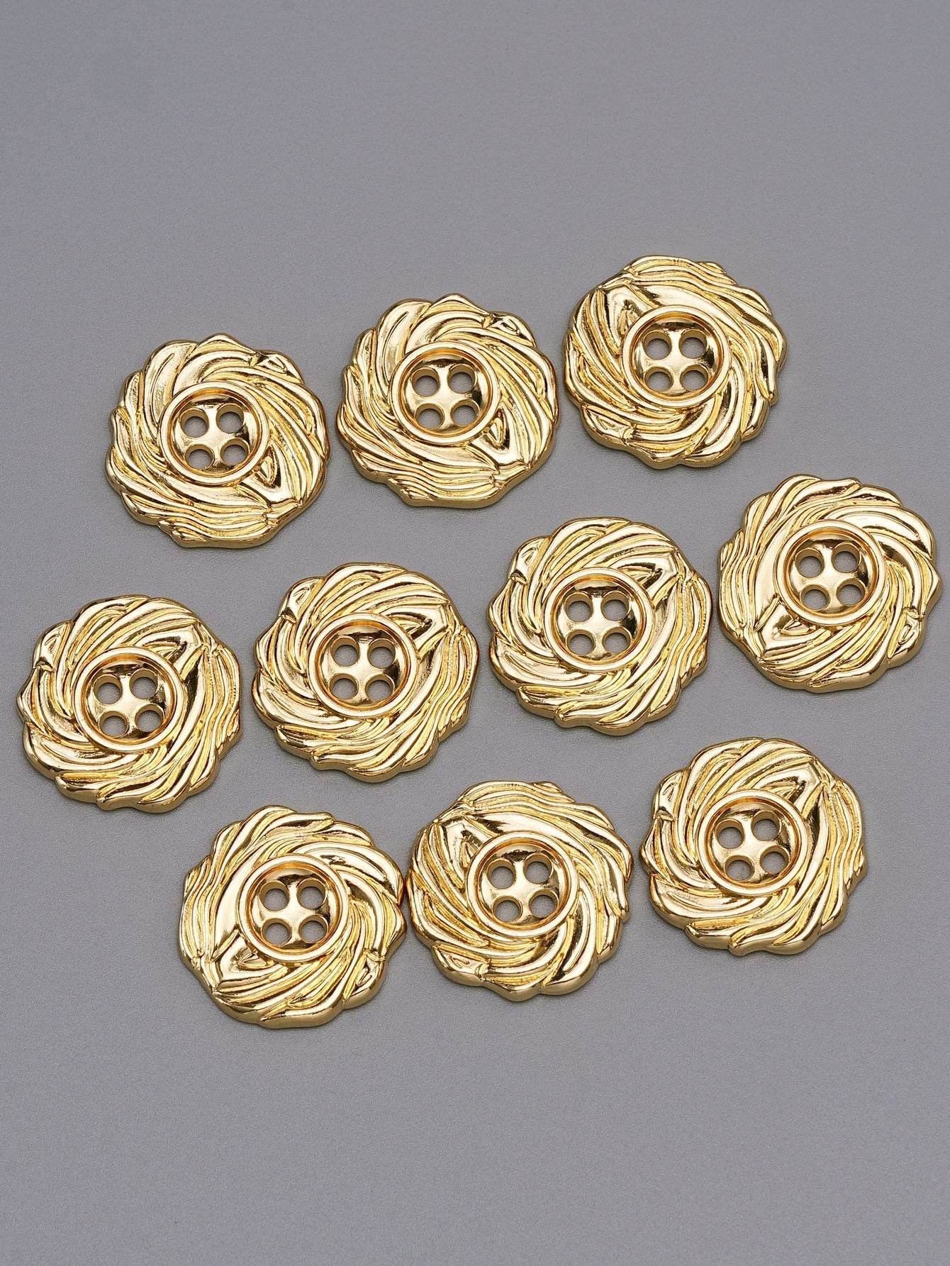 Gold 4-hole spiral metal buttons, assorted pieces laid out, front view