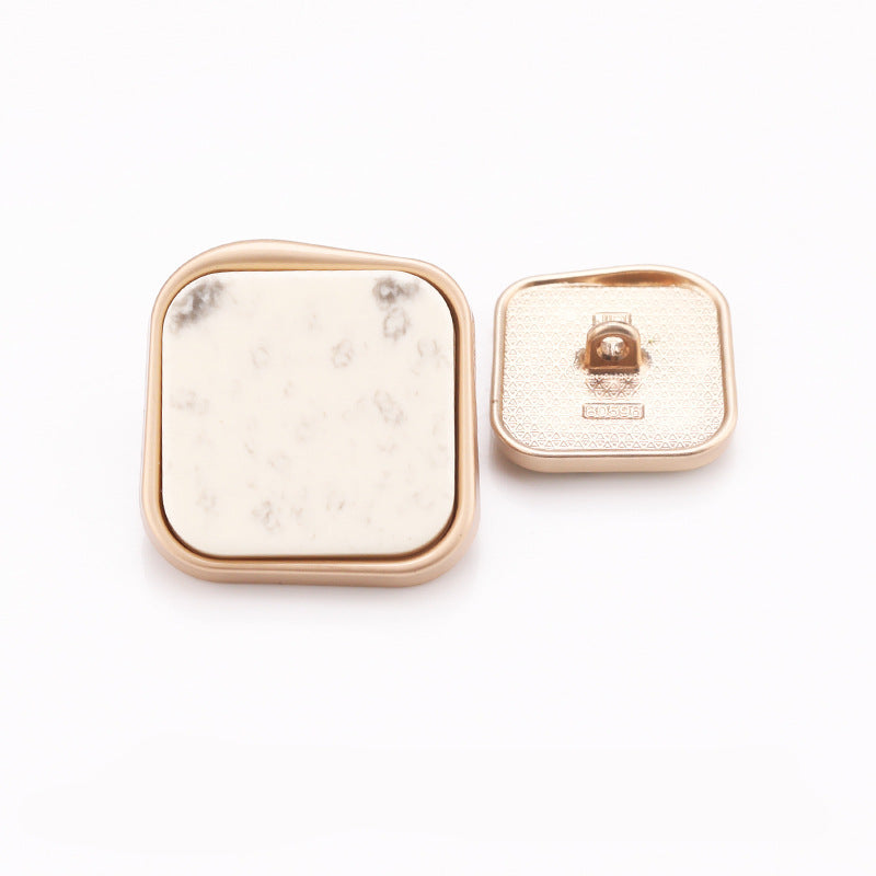 White marble square shank button with subtle speckles, gold frame; back shows pin