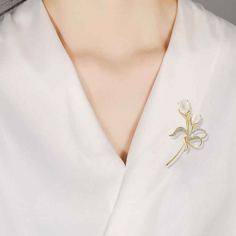 Tulip brooch on lapel in gold tone with beige cat’s-eye stone