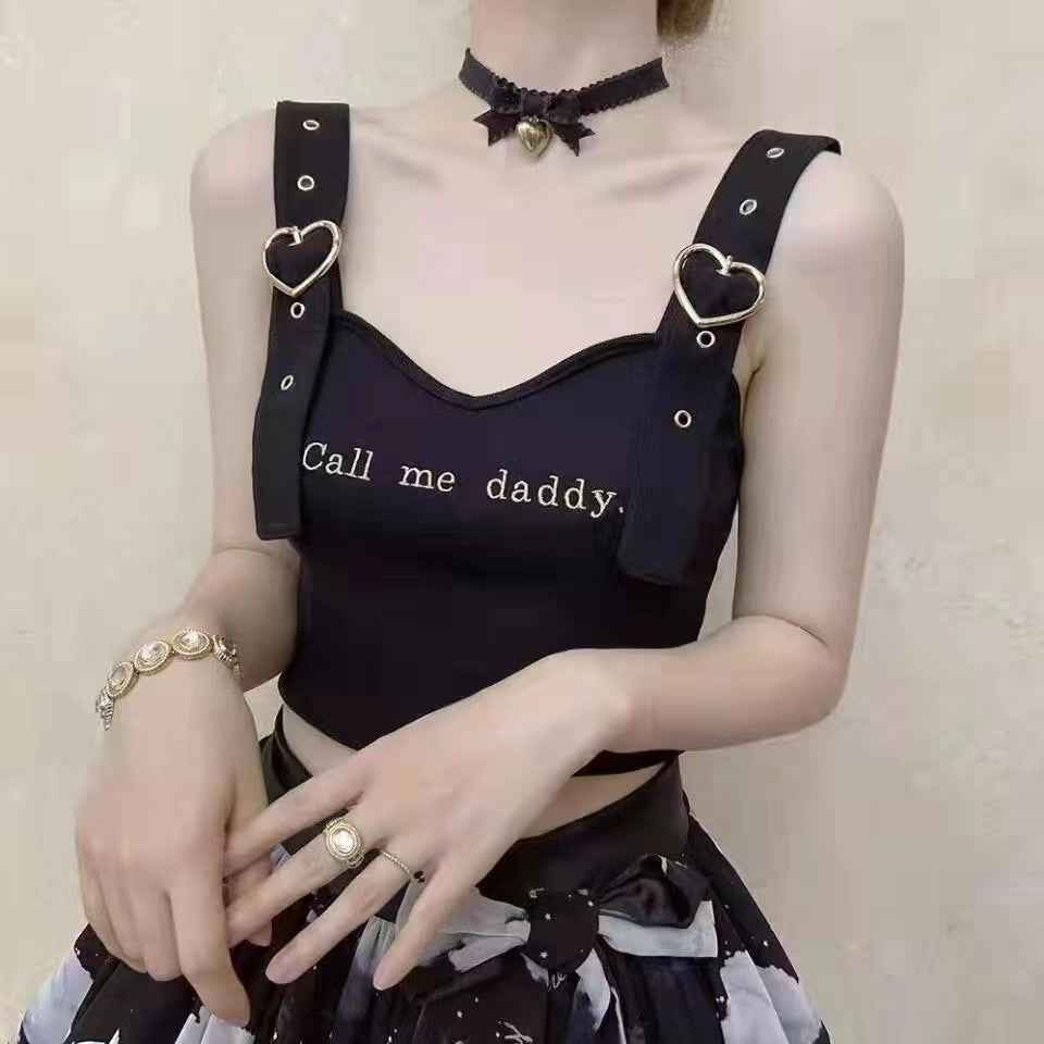 Heart-shaped roller buckle on black straps of a dark sleeveless top