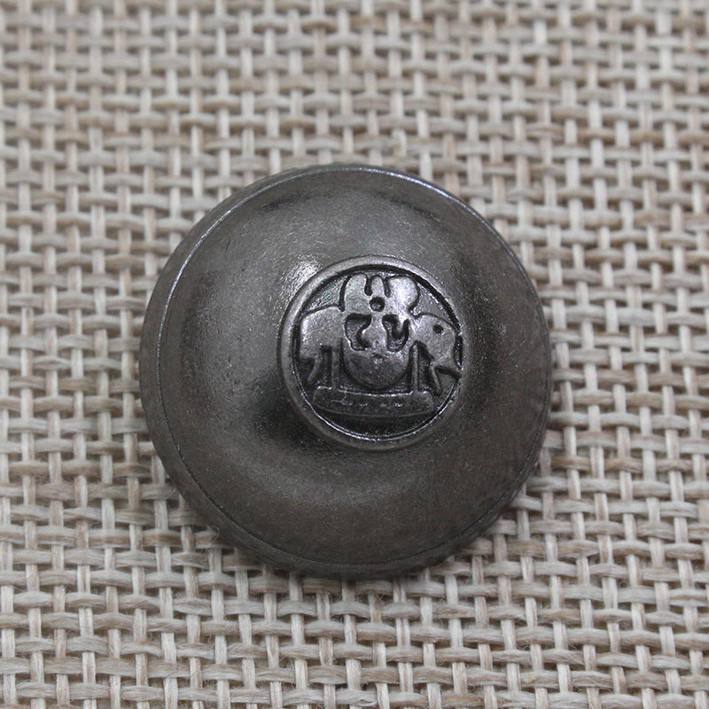 Ein einzelner runder Knopf, dunkelgrau-bronze, geprägtes Kronen-Emblem