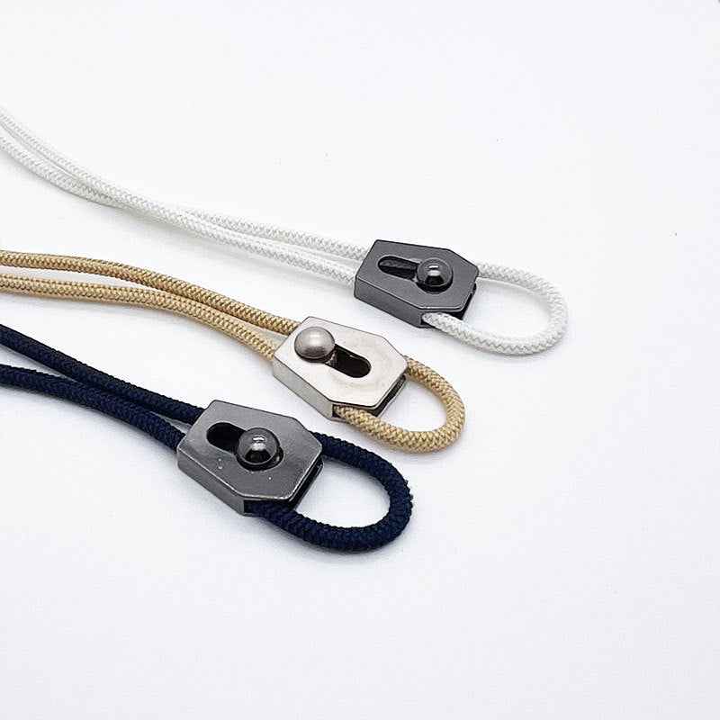 Metal cord adjuster stoppers on white, beige, and navy drawstrings—silver and black
