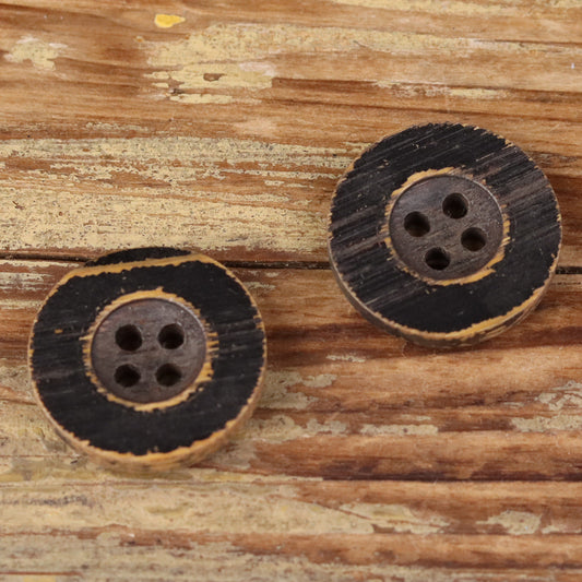 Two round black distressed wood buttons with four holes each.