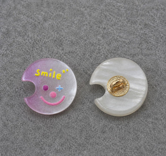 Purple moon-shaped resin shank button with yellow smiley face; gold back shank detail