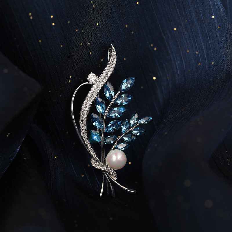 Floral bouquet brooch with curved silver frame, blue crystals and white freshwater pearl.