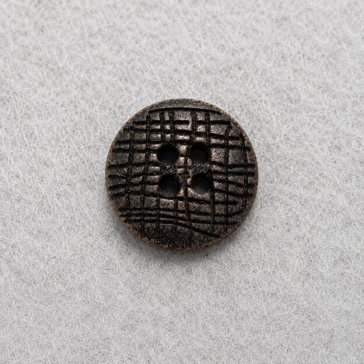 Dark brown flat round wood button with carved floral grid and four holes