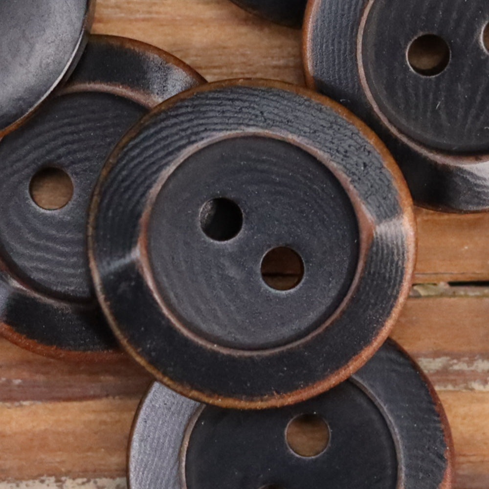 Dark round 2-hole buttons with scorched rim edge and textured grain