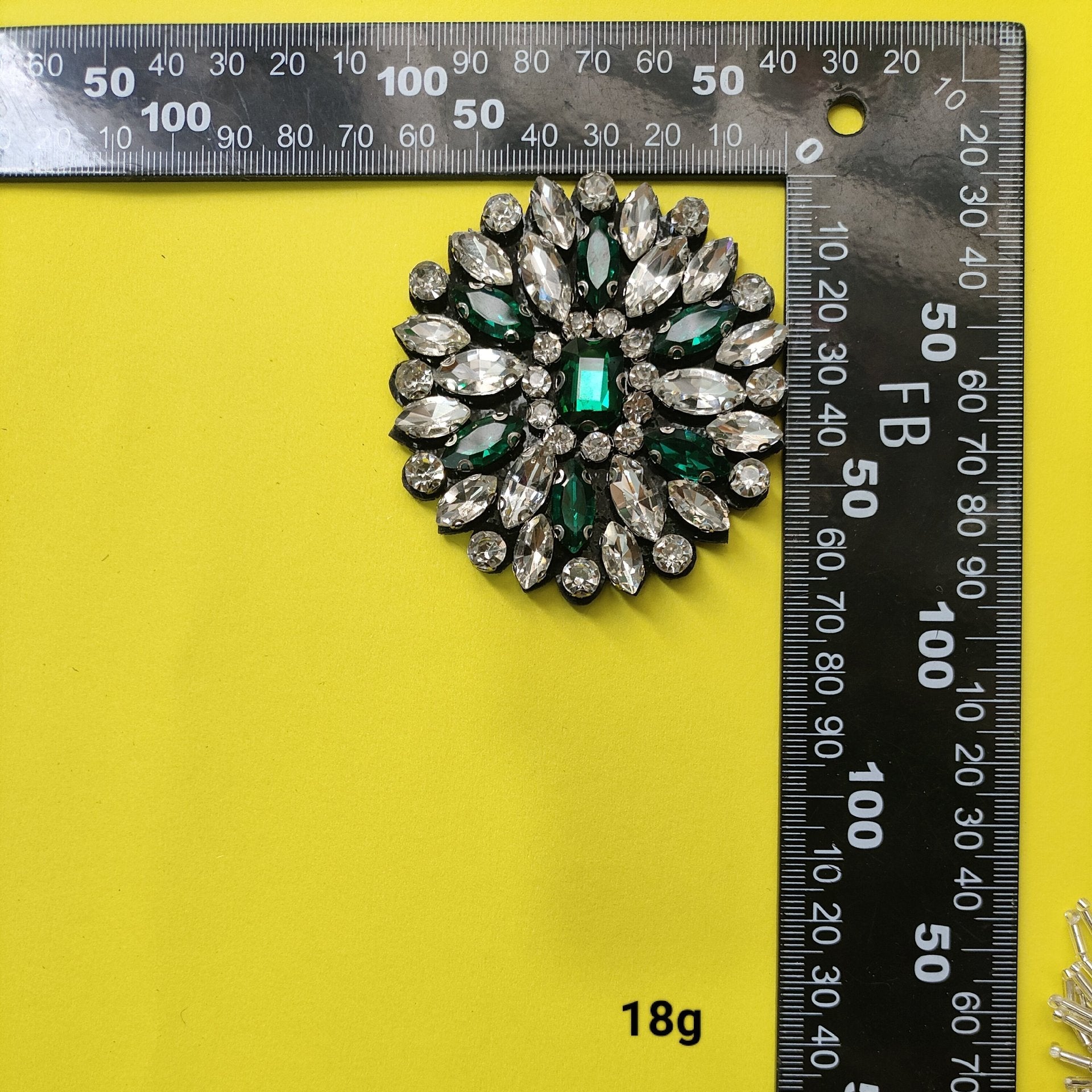 Silver beaded flower patch with oval gems and green center accents, shown with ruler scale